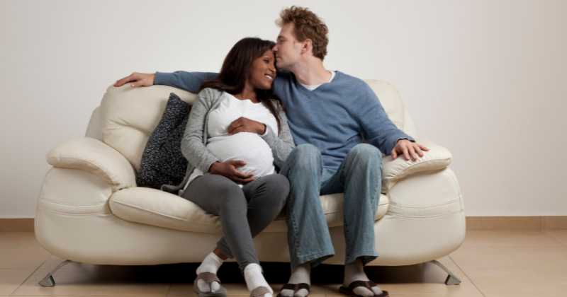 pregnant couple cuddling on the couch.
